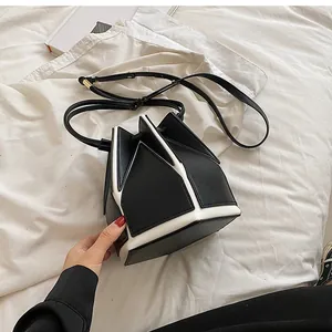 Close-up of structured black and white bucket bag with artistic origami leather folding design