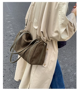 Gros plan d'un sac hobo en daim marron avec bandoulière olive et coutures en cuir de luxe
