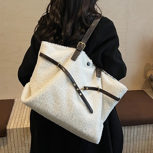 Minimalist white fuzzy tote bag with brown leather straps worn by model in black coat