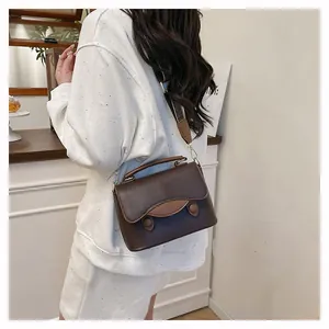 Détail du sac bandoulière en cuir grainé marron foncé avec empiècement marron clair