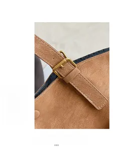 Detail of adjustable gold buckle and fine stitching on brown lychee grain leather tote