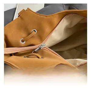 Close-up of brown suede tote bag featuring silver eyelets and smooth zipper closure