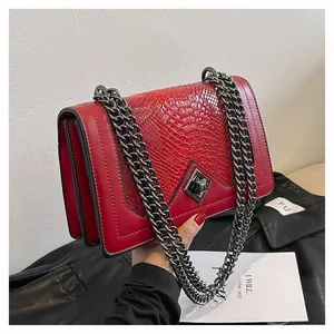 Detail of red snake pattern handbag featuring dark grey chain and turn-lock closure