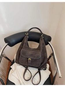 Détail du sac Hobo marron foncé avec coutures contrastées sur un fauteuil en cuir