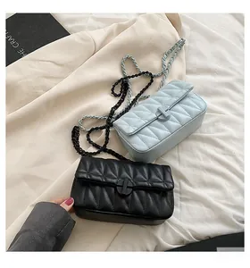 Detail of quilted leather texture and chain straps on black and light blue crossbody bags