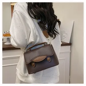 Sacoche en cuir marron grainé sur un mannequin avec bandoulière large et réglable