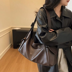 Minimalistische grote donkerbruine leren hobo-tas met brede riem op een model