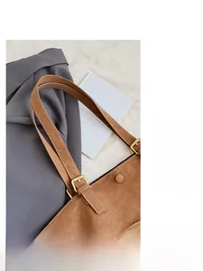Detail shot of brown leather tote bag with gold metal buckle and adjustable strap