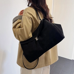 Minimalist black matte suede shoulder bag with silver buckle worn by a model