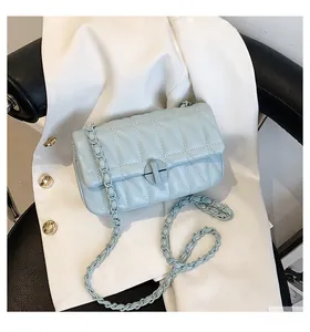 Detail of light blue quilted chain bag with diamond stitching and circular metal lock