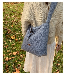 Close-up of blue faux shearling tote bag with brown drawstring detail and leather tag