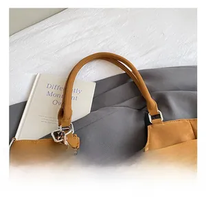 Detail of tan suede tote bag handles with silver buckles and heart leopard charm