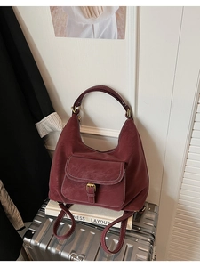 Détail du sac fourre-tout bordeaux avec coutures blanches et boucle en bronze