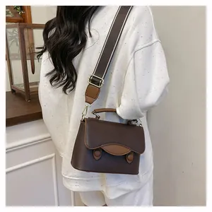 Détails d'un sac bandoulière vintage en cuir grainé avec large bandoulière rayée