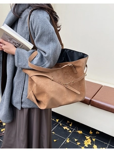Detailed side view of large brown vintage tote bag with metal buckle on a model