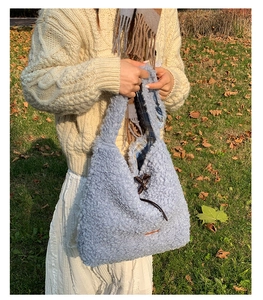 Detail of light blue fleece tote bag featuring interior plaid lining and horn buckle closure
