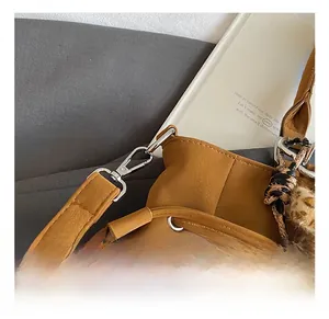 Detail of silver metal hook on a brown faux leather tote bag with leopard scarf