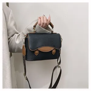 Gros plan détaillé d'un sac en cuir noir avec bordure marron et bandoulière large élégante