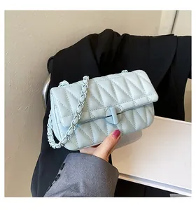 Detail of light blue quilted crossbody bag with metal twist lock and chain strap