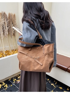 Brown textured leather tote bag styled with a grey winter coat in an autumn outdoor setting