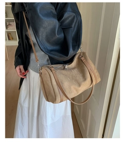 Détail d'un sac Boston vintage en daim beige avec finitions en cuir et fermeture éclair