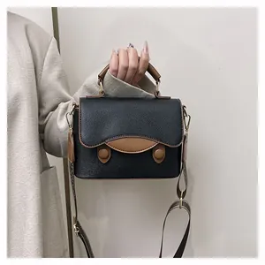 Détail du sac à main noir en cuir grainé avec bordure marron et bandoulière jacquard