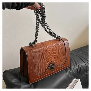 Detail of snake pattern texture and bronze geometric metal lock on a brown handbag