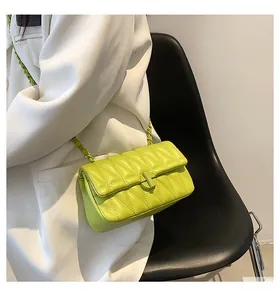 Detail of bright yellow quilted chain bag on white blazer for a stylish contrast
