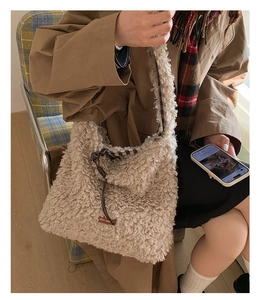 Detail of beige faux shearling tote bag with leather strap and plaid lining texture