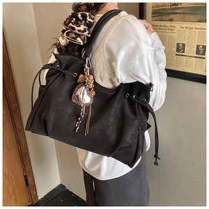 Detailed view of black matte tote bag with drawstring design and heart charm accessory