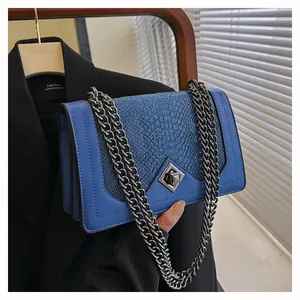 Close-up of royal blue snakeskin embossed crossbody bag with large silver geometric clasp