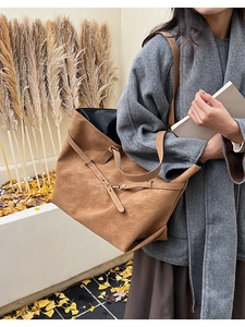 Detail of tan suede tote bag featuring a decorative metal buckle and premium texture