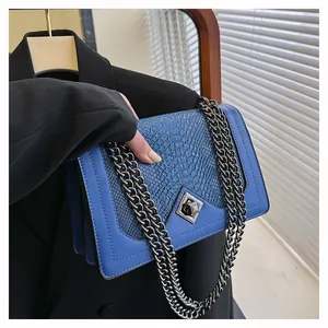 Macro shot of blue snakeskin patchwork handbag with diamond metal twist lock and chain