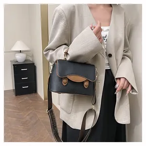 Détail du sac bandoulière contrasté avec sangle jacquard et finitions en métal doré