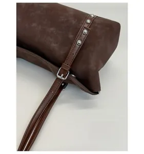 Detail of dark brown leather tote featuring vintage silver metal rivets and buckle strap