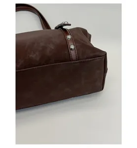 Detailed view of dark brown faux suede bag with silver rivets and reinforced bottom