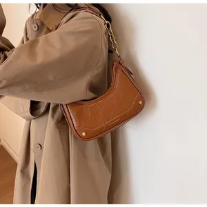 Detail of vintage brown crescent bag with gold chain strap and textured faux leather finish