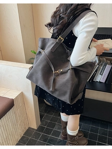 Detail of dark grey frosted tote bag showing the metal buckle and large capacity on model