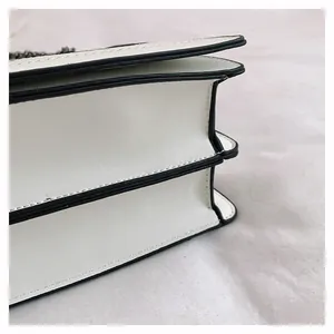 Detail of white leather shoulder bag with accordion fold structure and chain strap
