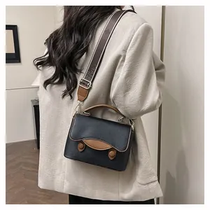 Détail d'un sac à main noir en cuir grainé avec une bandoulière en tissu jacquard sur mannequin