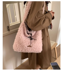 Detail of pink faux shearling tote bag with leather tag and black drawstring closure