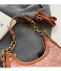 Macro detail of brown textured leather crescent bag with gold chain and strap