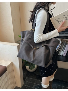 Detail of dark grey tote bag featuring adjustable gold metal buckle and matte texture