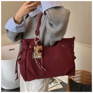 Detail of burgundy suede tote bag featuring drawstring side and leopard print charm