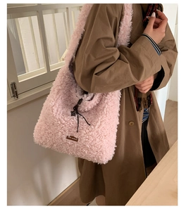 Detailed close-up of pink fuzzy fleece tote bag texture with brand leather tag and drawstring