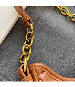 Close-up of golden chain strap and premium brown oil-wax leather on crescent bag