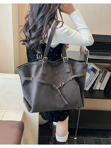Detail of dark grey leather tote bag with metal buckle on minimalist modern background