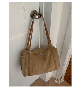 Close-up of brown suede pillow bag hanging on a door handle showing fine leather texture