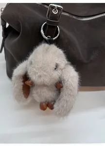 Dettaglio di un ciondolo a forma di coniglio di peluche con orecchie in pelle su borsa