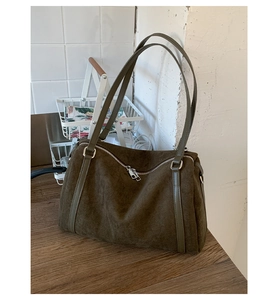Détail du sac Boston en daim vert olive avec double fermeture éclair et fines poignées